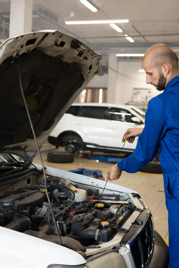 Kfz-Gutachter prüft Motorraum eines Fahrzeugs mit geöffneter Motorhaube in der Werkstatt